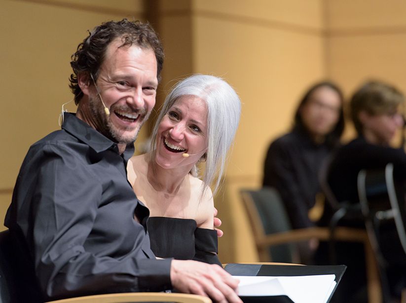 Closeup of a man and woman dressed in black smiling with their arms around each other at a Visible Ink performance.