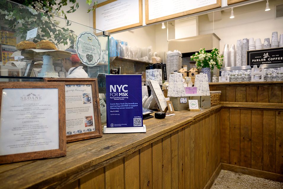 A sign reading “NYC for MSK” sits atop a counter in a café. 